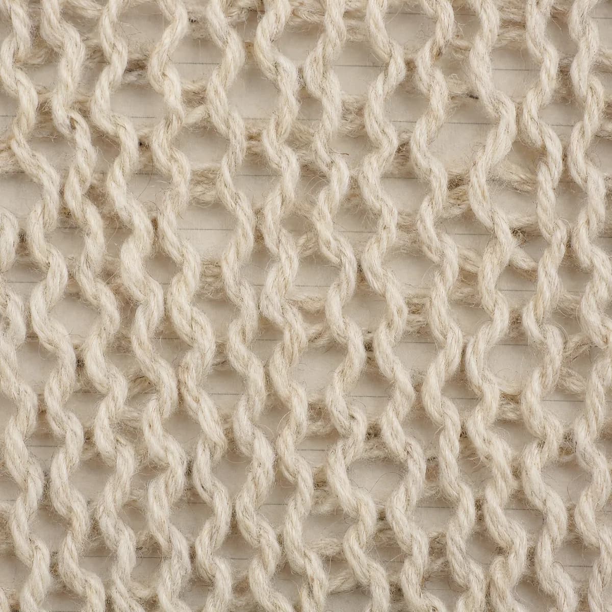 Extreme close-up of a coarse open knit with large loose stitches and visible gaps between the loops.