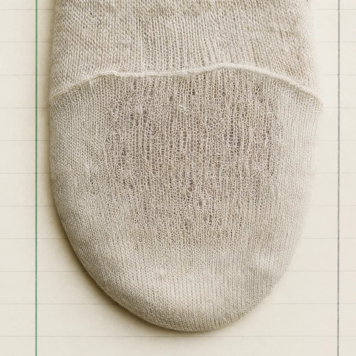 Extreme close-up of a sock toe where the knit has thinned to near transparency without yet breaking.