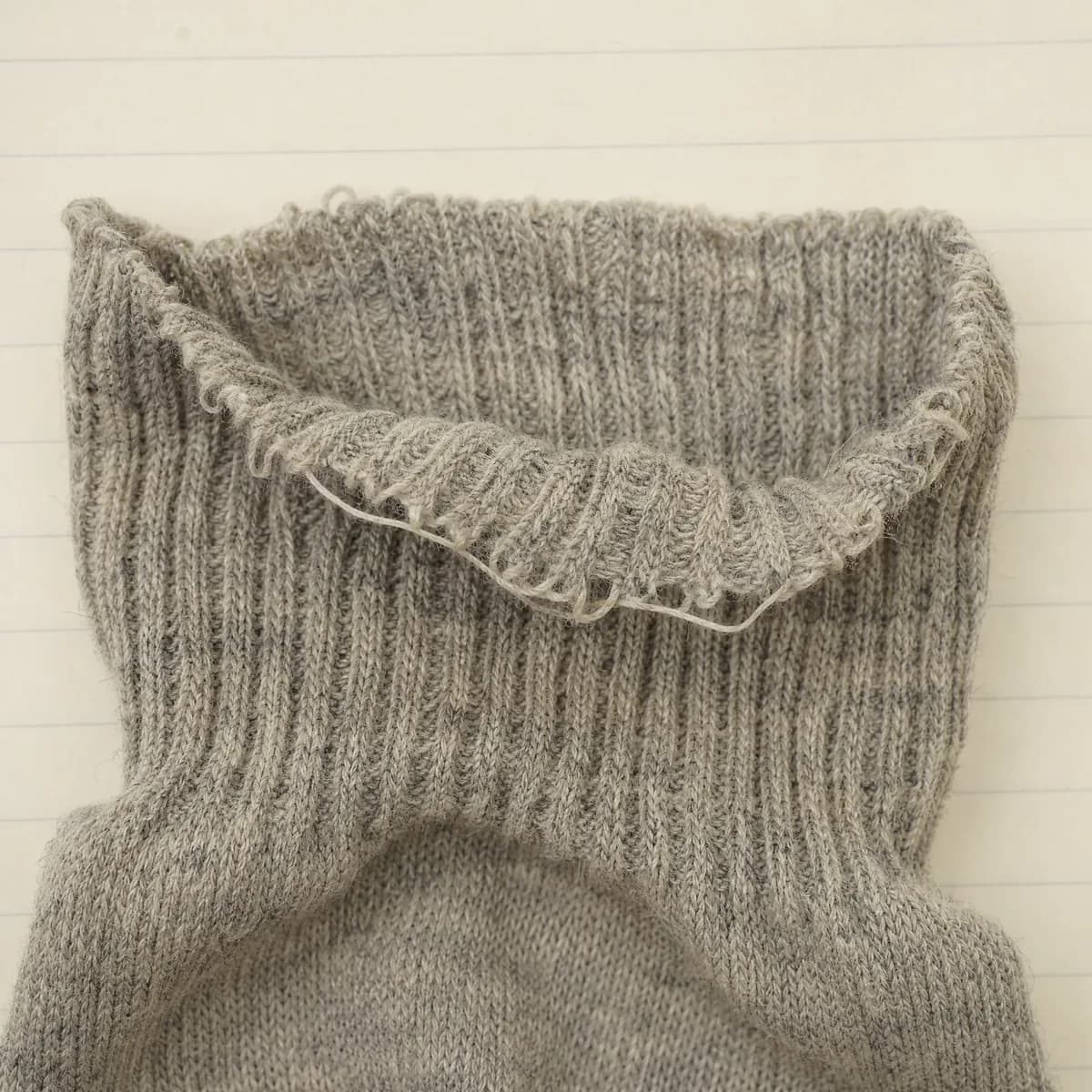 Extreme close-up of a slack sock cuff whose ribbing has splayed open and no longer gathers.