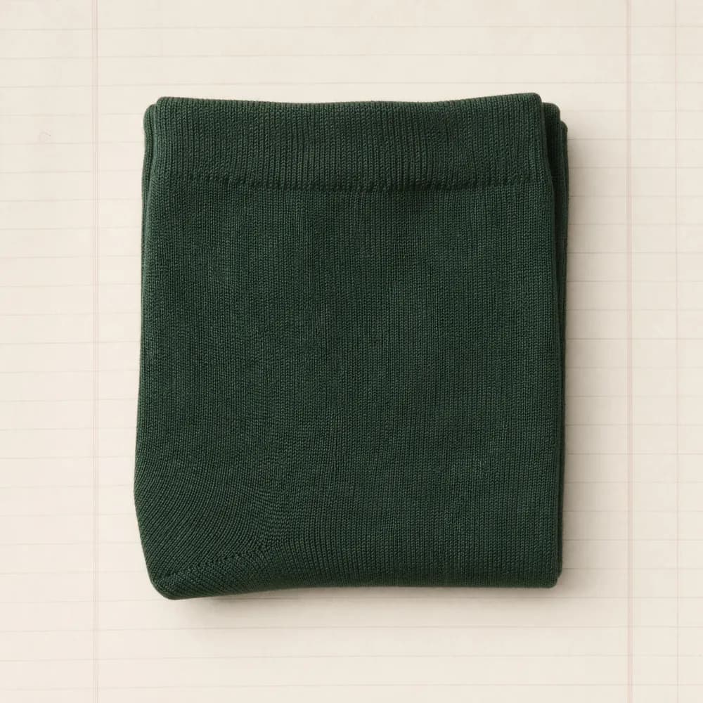 A fine merino sock folded into a flat square on ruled paper.